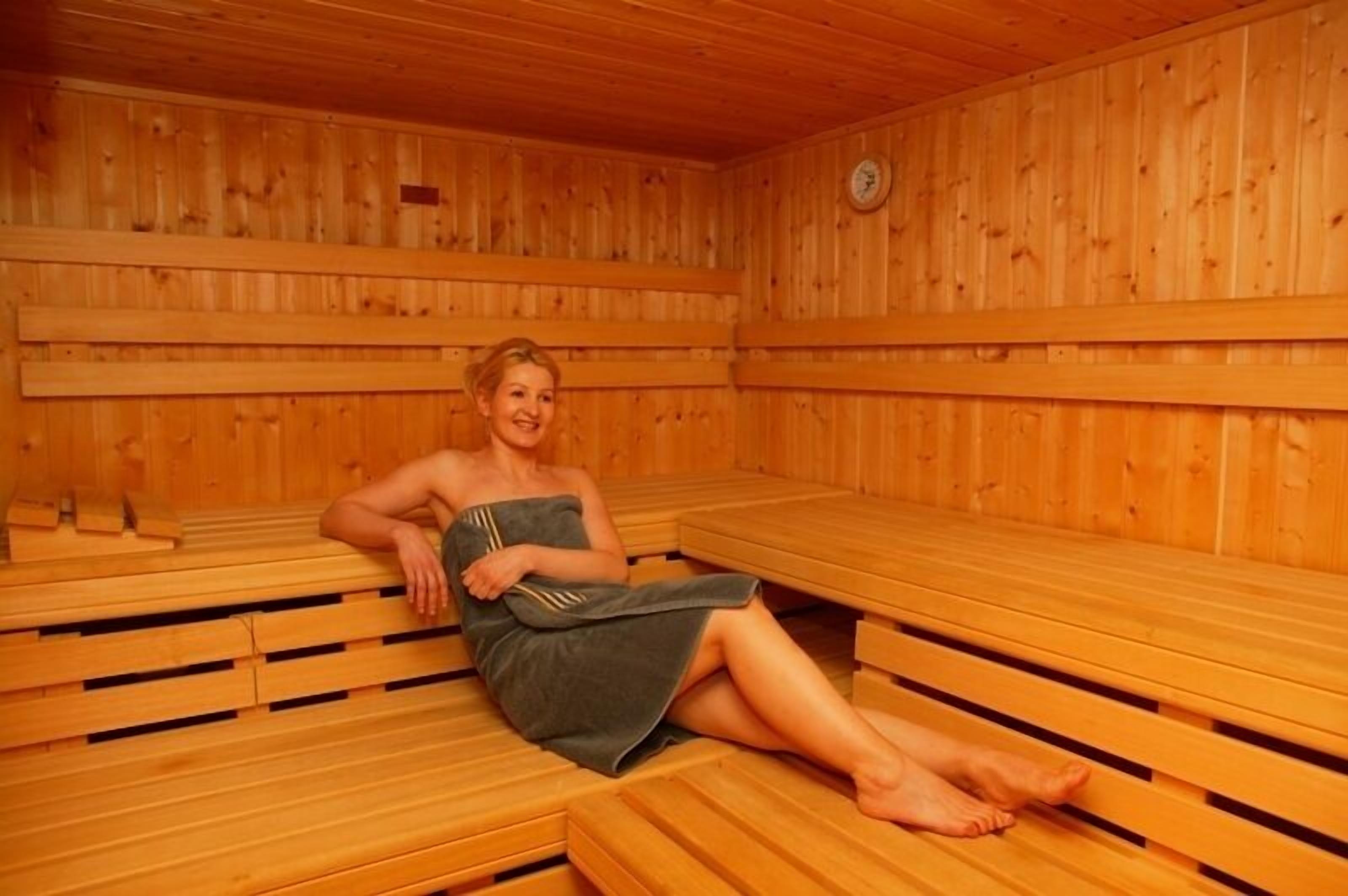 Un sauna con bancos de madera y una persona sentada en uno de ellos.