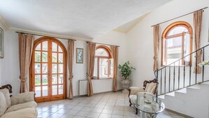 Ein geräumiges Wohnzimmer mit einem großen Bogenfenster, einer Treppe und einer bequemen Couch.