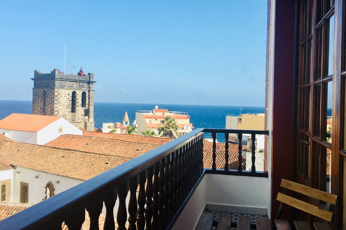 Ein Balkon mit Blick auf das Meer und einen historischen Turm.