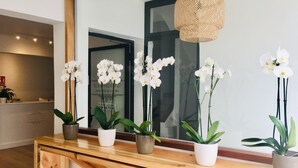 Mostrador de recepción con encimera de madera, plantas en macetas y una lámpara colgante.