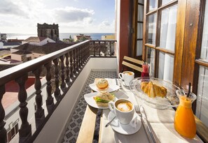 A balcony with a table set for breakfast, including a sandwich, coffee, and juice. - El Hotelito 27 (Santa Cruz de la Palma)