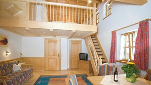 Un'ampia zona giorno con soffitto alto, scala in legno e un'accogliente area salotto.