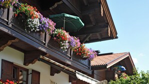 Un edificio tradizionale in legno con fioriere sul balcone e una struttura in legno a fitta struttura in primo piano.