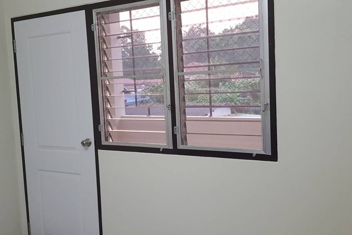 A room with a white door and a window with metal bars.