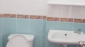 A bathroom with a toilet, sink, and tiled walls.
