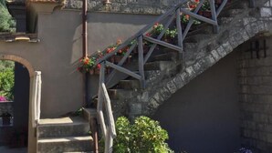 A stone building with a staircase leading to a window. There are potted plants and flowers along the steps. - Agriturismo Il Convento (Massa Lubrense)