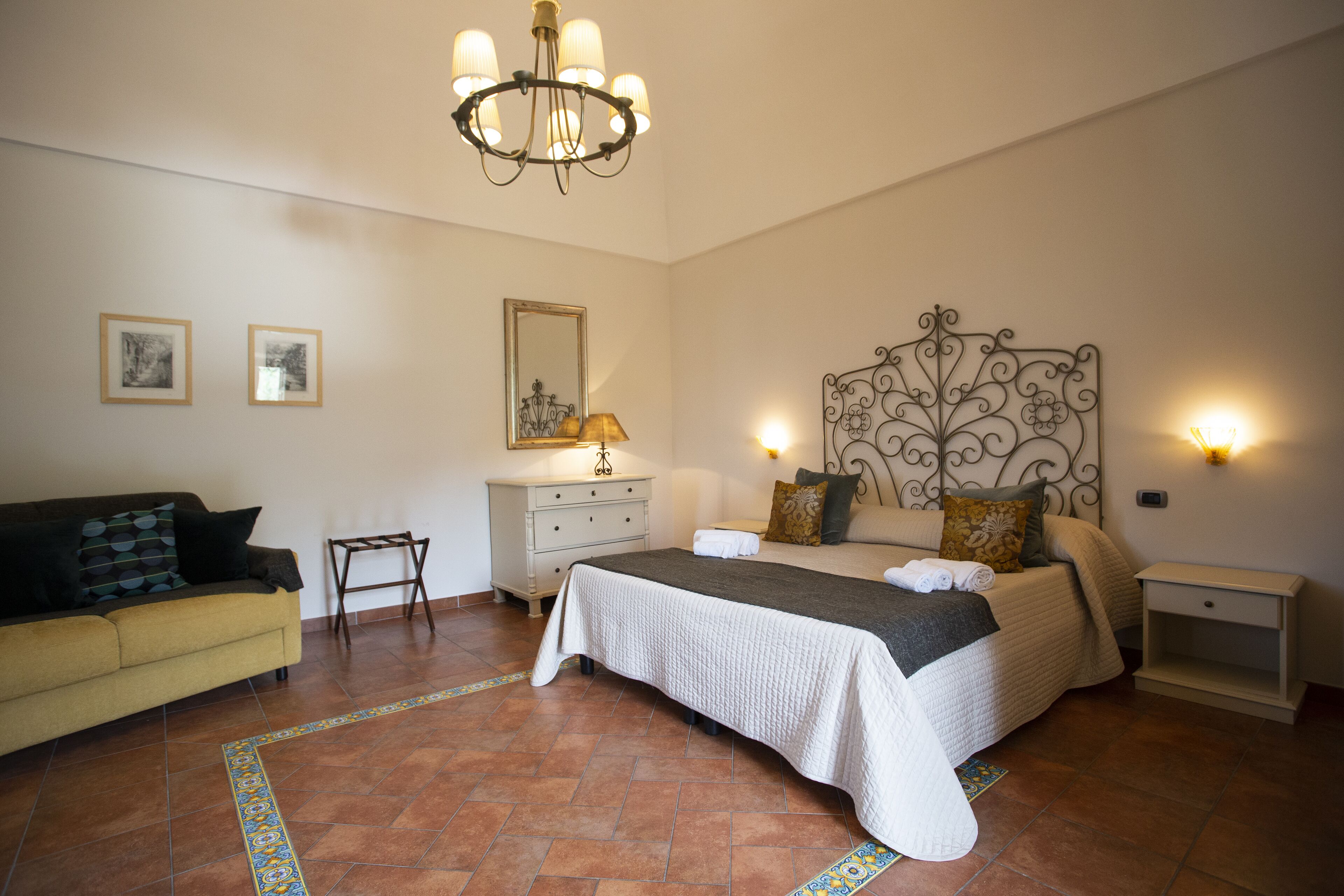 Un dormitorio con cama, mesita de noche, cómoda, silla y sofá.