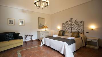 Un dormitorio con cama, mesita de noche, cómoda, silla y sofá.