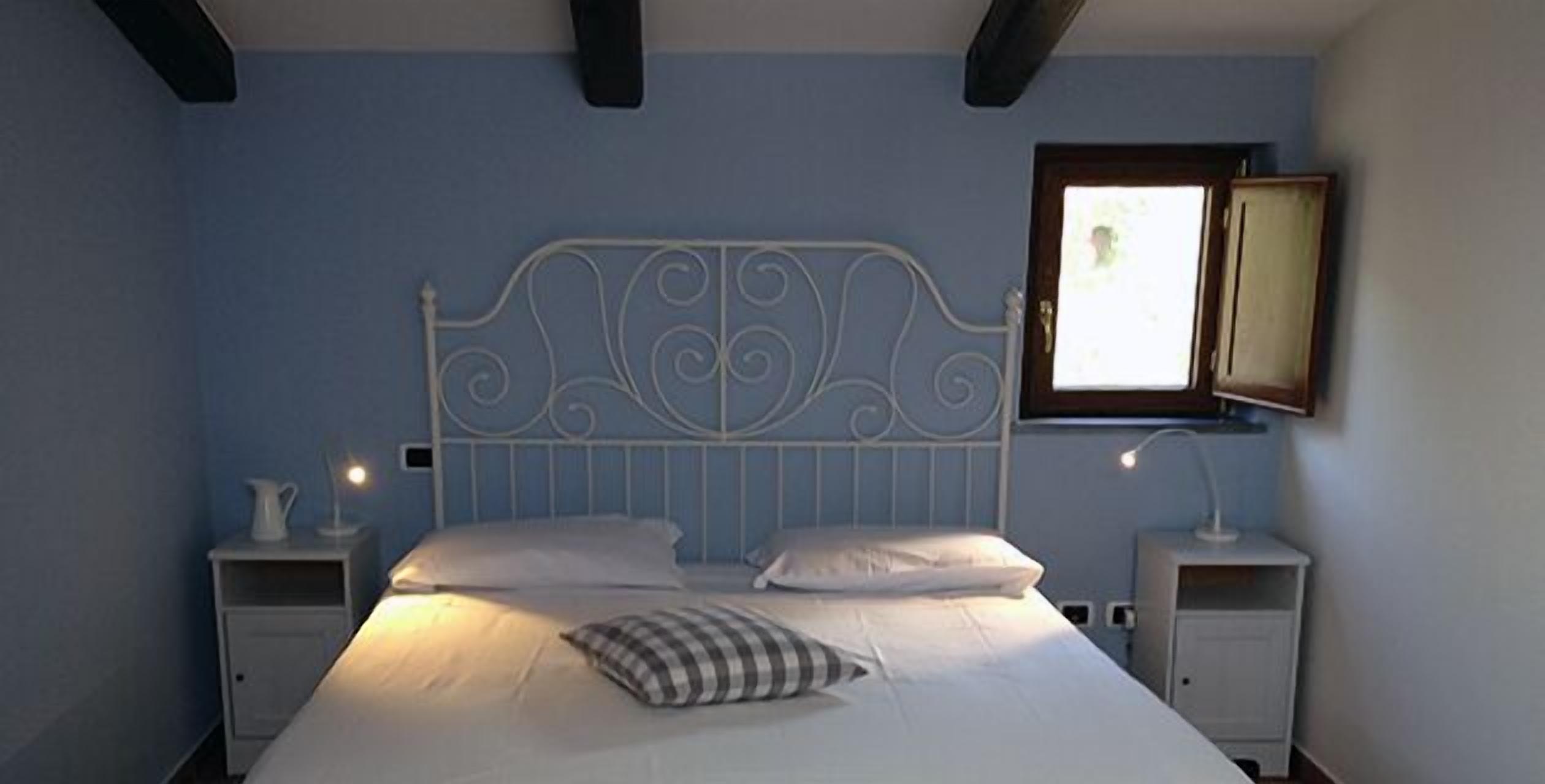 A bedroom with a bed, two bedside tables, a window, and a mirror.