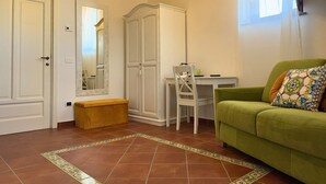 A room with a green sofa, a white desk, a wardrobe, and a bench. - Agriturismo Il Convento (Massa Lubrense)