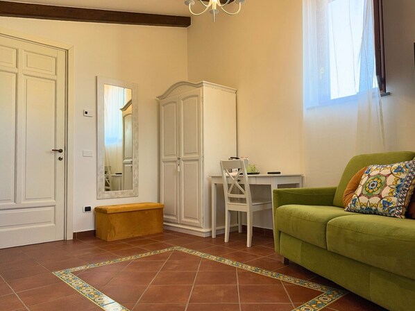A room with a green sofa, a white desk, a wardrobe, and a bench. - Agriturismo Il Convento (Massa Lubrense)