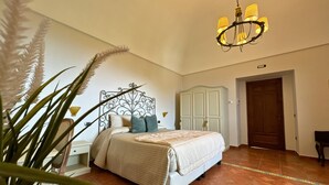 A bedroom with a bed, nightstand, dresser, and a chandelier. - Agriturismo Il Convento (Massa Lubrense)
