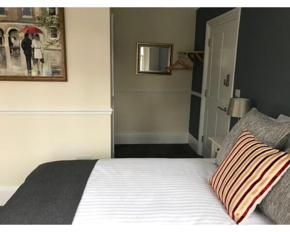 A hotel room with a bed, a painting, a mirror, and a wardrobe. - Iffley Town House (Oxford)
