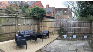 A patio area with a wooden deck, outdoor furniture, and potted plants. - Iffley Town House (Oxford)