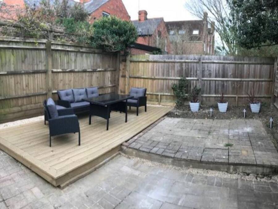 Un espace patio avec une terrasse en bois, du mobilier d’extérieur et des plantes en pot.