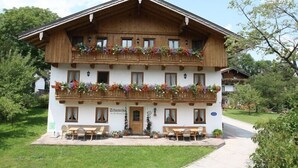 A traditional wooden building with a balcony adorned with flowers, a sign reading "Zuchterhaus," and outdoor seating.