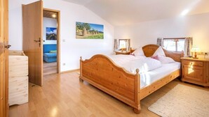 Un dormitorio con una cama de madera, una mesita de noche, un armario y una puerta que da a otra habitación.