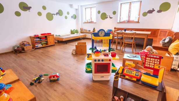 A children's playroom with wooden flooring, a play kitchen, and educational toys.