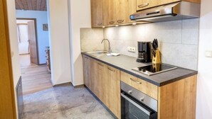 Una cocina moderna con armarios de madera, un lavamanos de acero inoxidable y un horno empotrado.