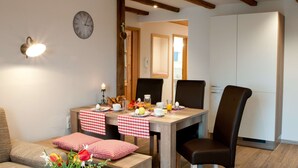 Ein Essbereich mit einem Holztisch, gedeckt für das Frühstück, einer Uhr an der Wand und einer gemütlichen Sitzgruppe.