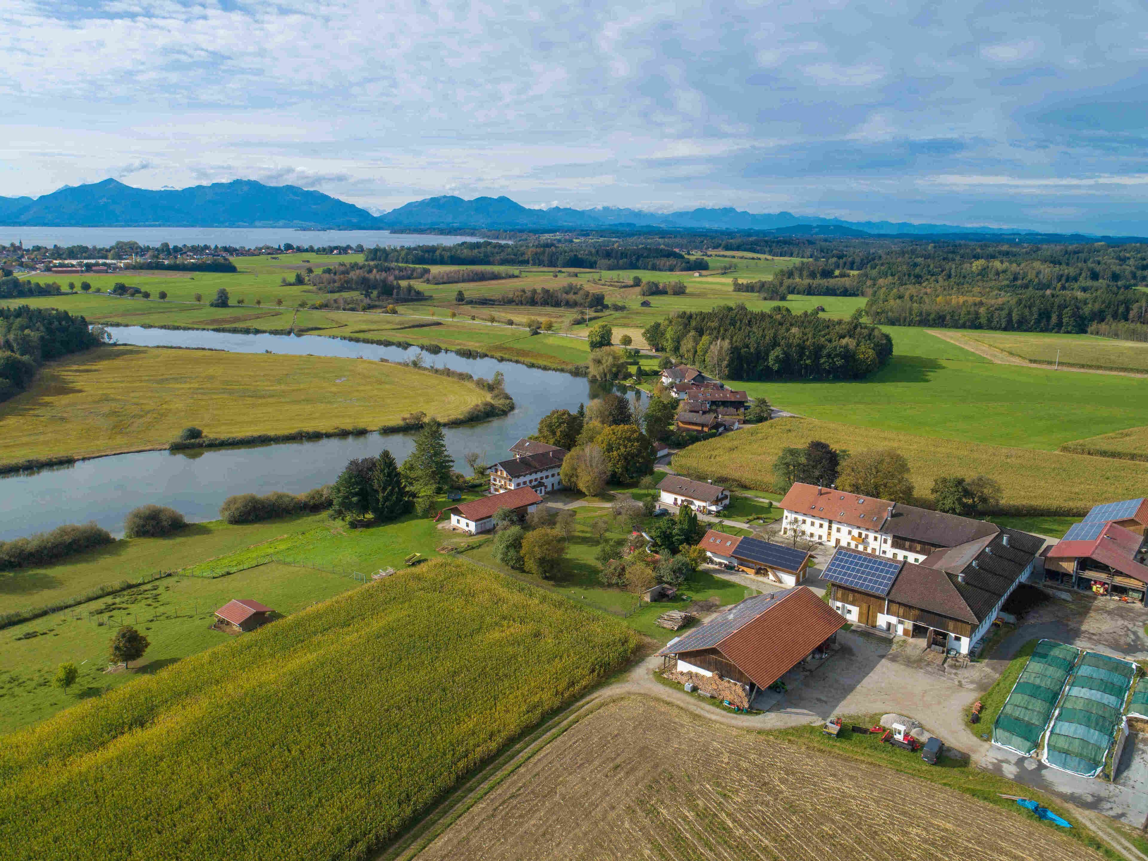 Paisaje rural con un río, campos y algunos edificios.