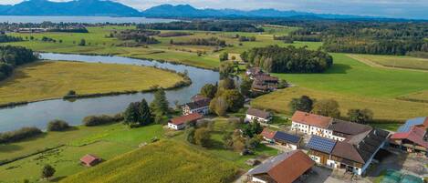 Paisaje rural con un río, campos y algunos edificios.