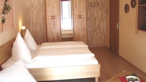A bedroom with a wooden bed, a red chair, and a small table with a decorative item. - sonnige, ruhige, zentrale Ferienwohnung mit Bergblick am Rupertuspark (Bad Reichenhall)