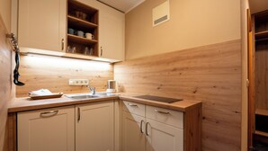 A compact kitchen with white cabinets, a wooden countertop, a sink, and a coffee maker.