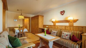 A cozy room with a wooden bench, a dining table, and a sofa.