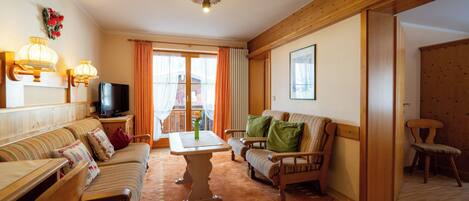 A cozy living room with a sofa set, a dining table, and a television.