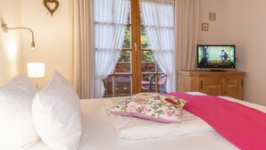 Une chambre à coucher avec un lit, une télévision et une fenêtre avec des rideaux.