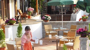 An outdoor patio area with wicker furniture, stone walls, and potted plants.