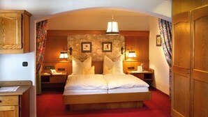 Ein Schlafzimmer mit einem großen Bett, einem Holzkopfteil, zwei Nachttischen mit Lampen und einem roten Teppich.