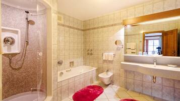 Ein Badezimmer mit Dusche, Badewanne und Waschbecken, mit gefliestem Boden und einem Spiegel über dem Waschbecken.