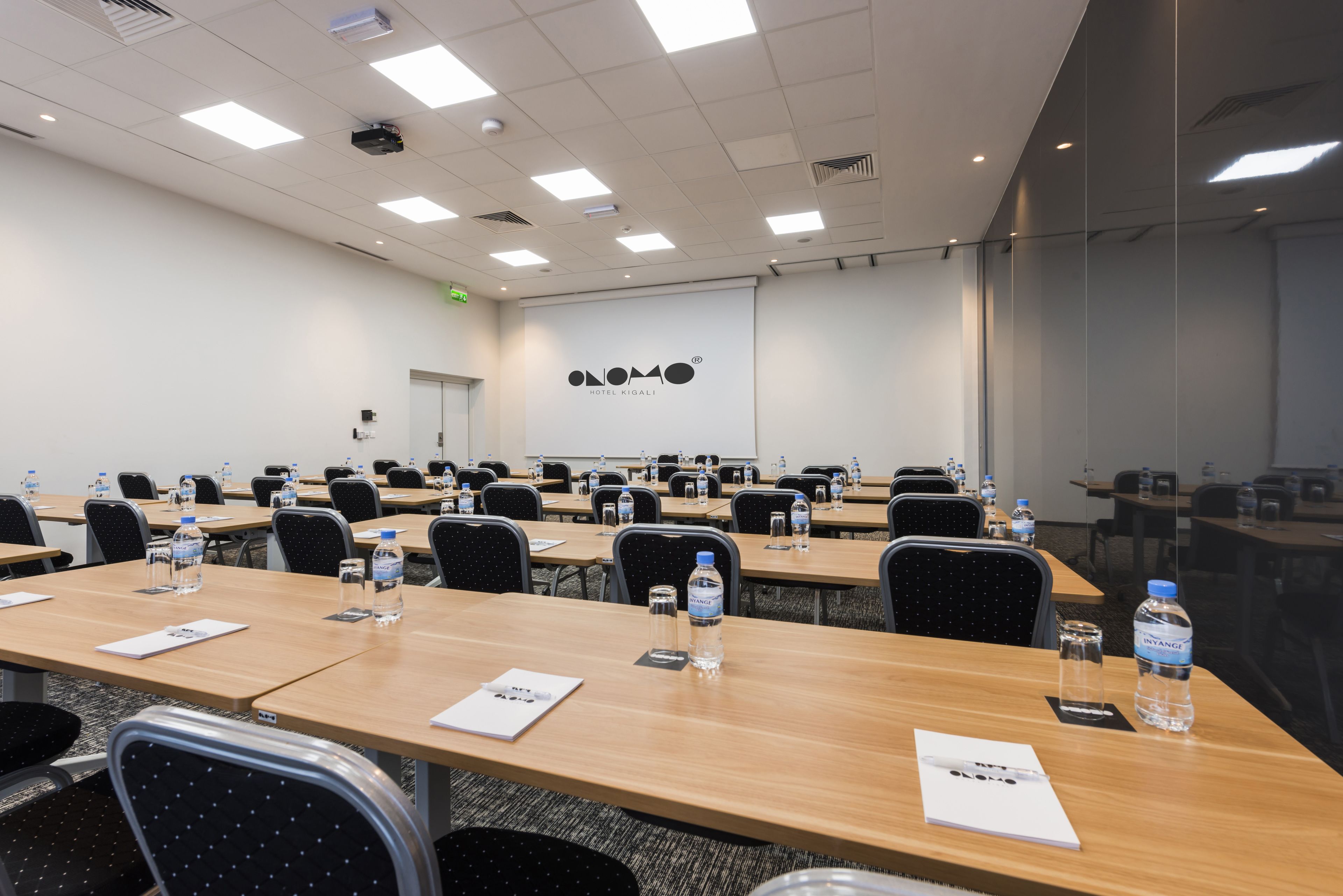 A conference room with multiple tables, chairs, and water bottles.