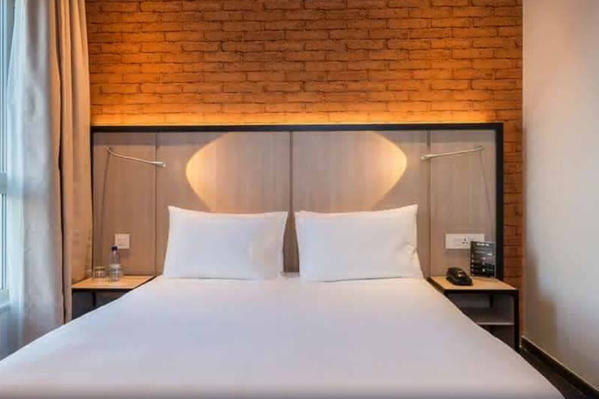 Camera d'albergo con un letto grande, un muro in mattoni e vista sulla città.