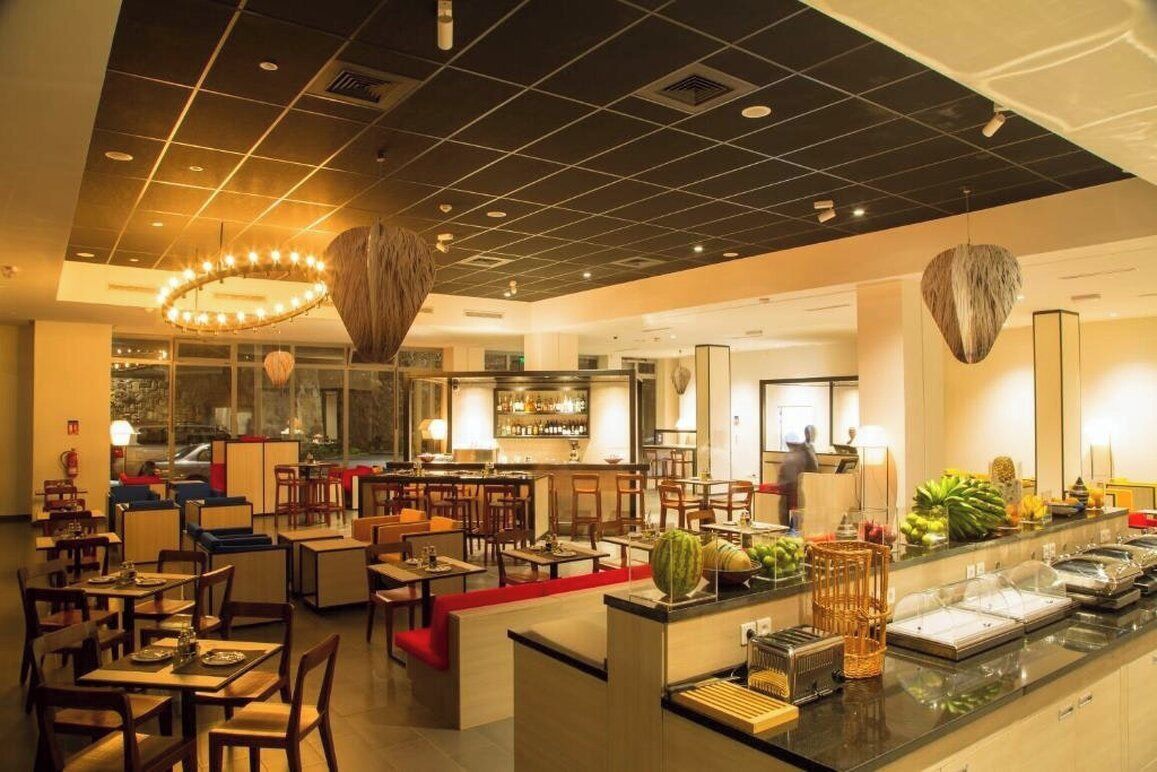 A modern restaurant with a bar area, seating arrangements, and a buffet counter.