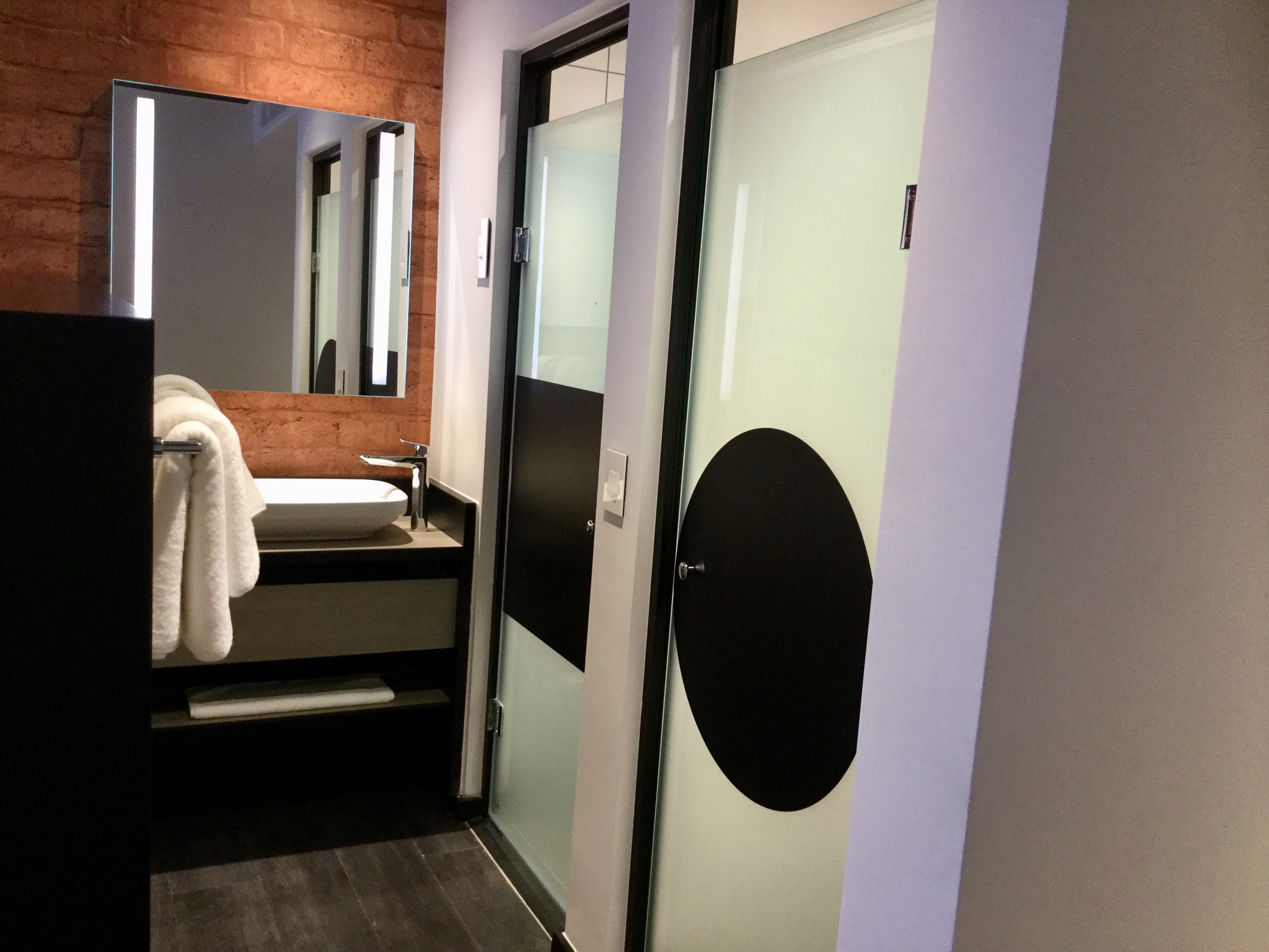 A modern bathroom with a white sink, a mirror, and a towel hanging on the wall.