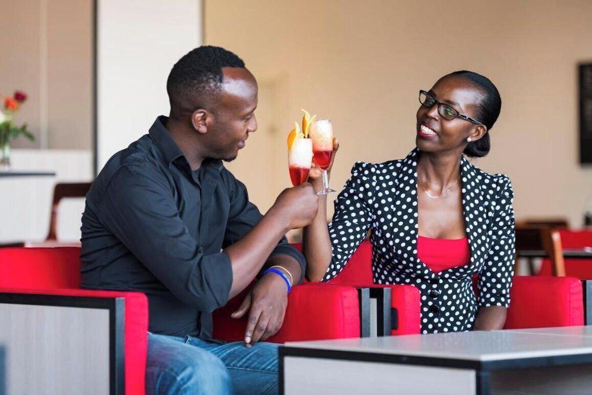 A man and a woman sitting at a table in a restaurant with red seating.
