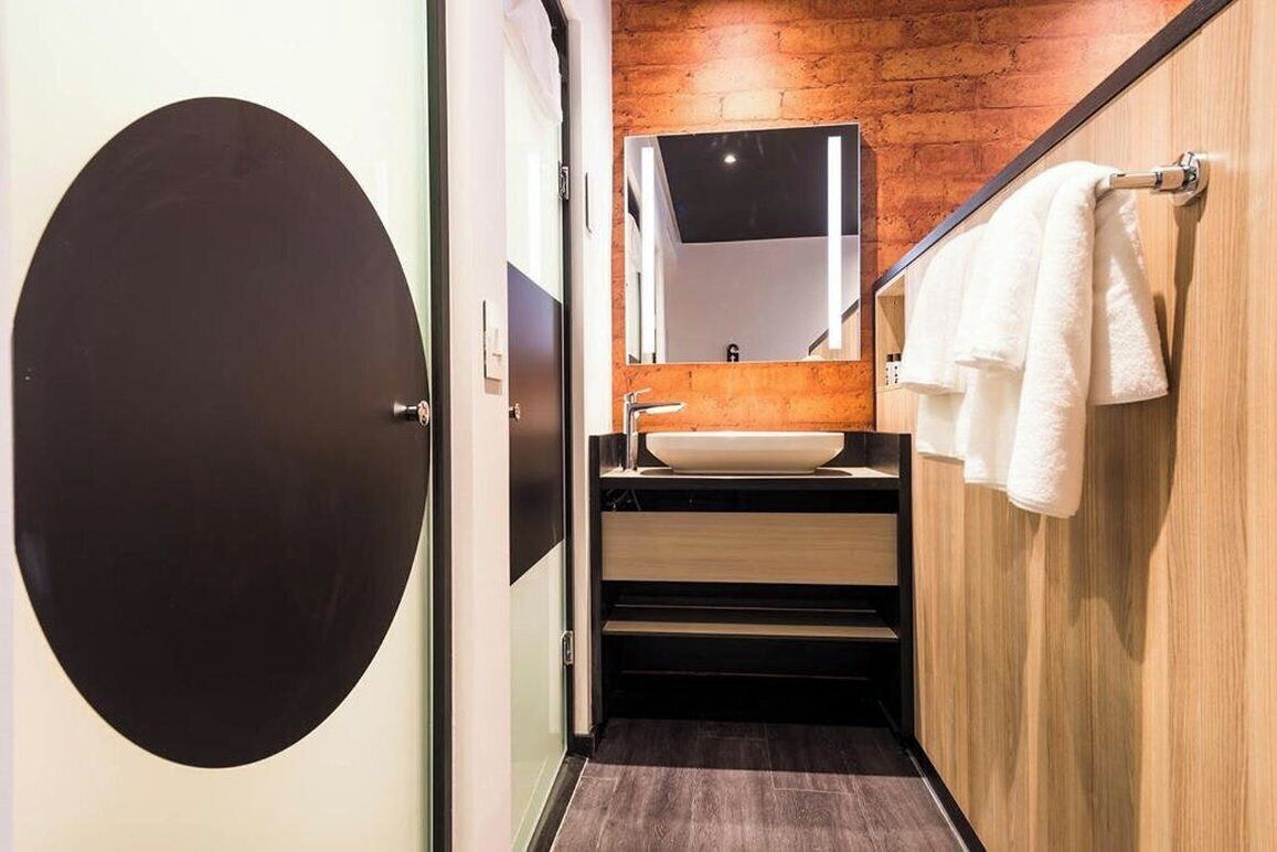 Un baño moderno con un espejo grande, un lavamanos y un perchero para toallas.