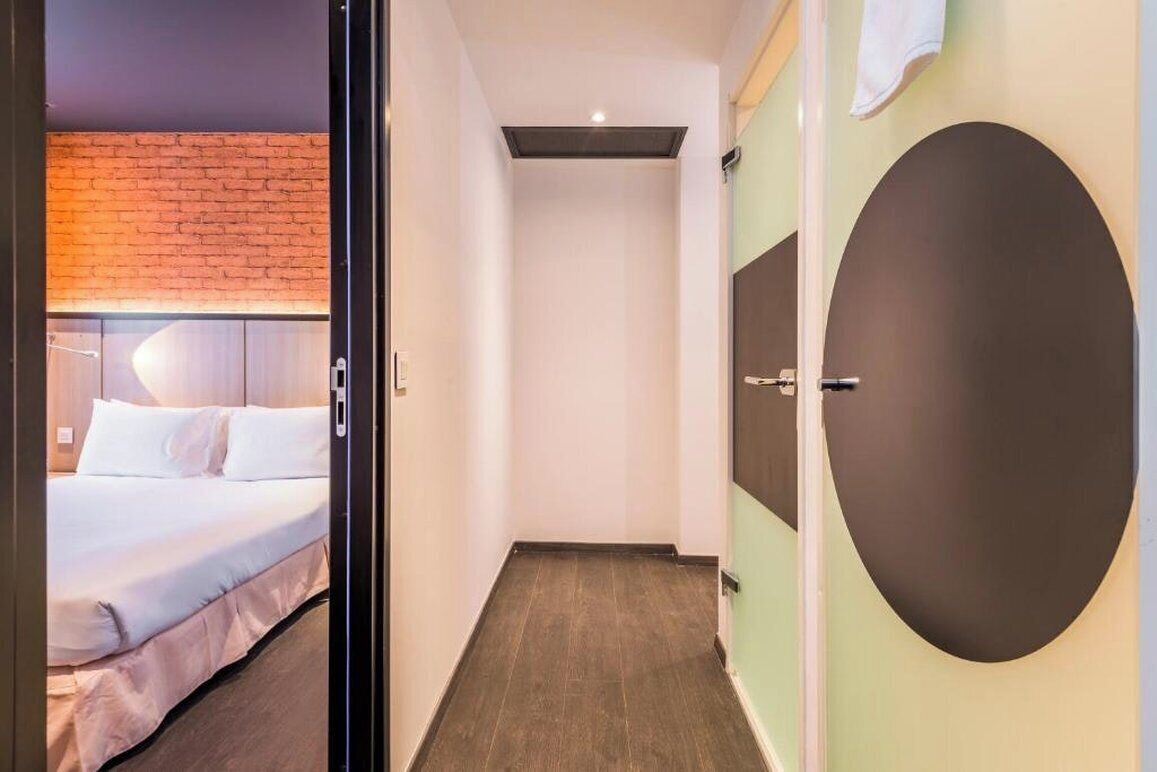 A hotel room with a bed, a wardrobe, and a door.