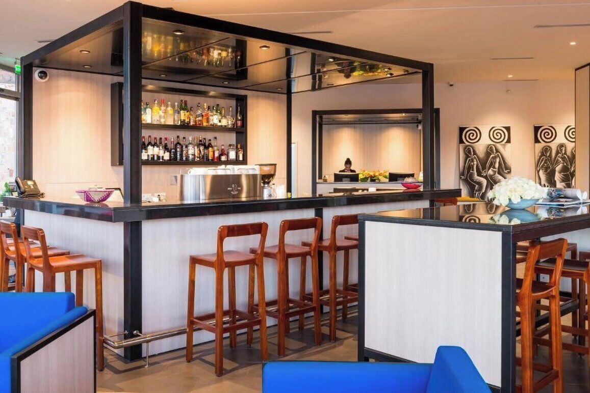 A bar area with a counter, bar stools, and a variety of bottles.
