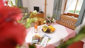Una mesa de comedor con un frutero, una botella y una revista.