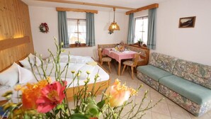 Una habitación acogedora con cama, sofá, mesa de comedor con sillas y ventana con cortinas.