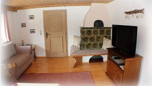 Een woonkamer met een bank, een lange zitbank, een televisie op een houten dressoir, en een kast.
