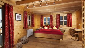 Ein Schlafzimmer einer Holzhütte mit einem Bett, einem Schreibtisch und einem Stuhl.