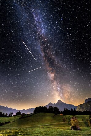A starry night sky over a mountainous landscape with a visible Milky Way.