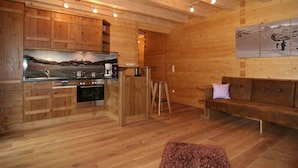 Ein Holzblockhaus-Interieur mit Küche, Essbereich und einer Couch.