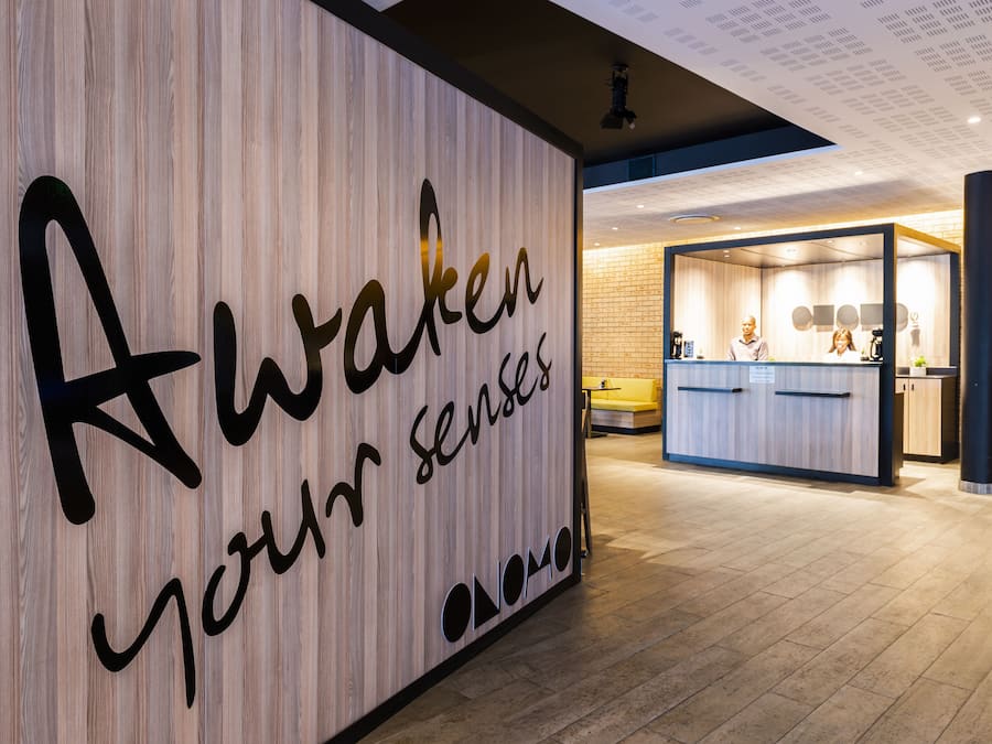 Un espace d’accueil avec un mur en bois sur lequel est inscrit le texte « Réveillez vos sens » et un comptoir d’accueil au design moderne.