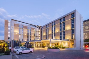 Un hôtel moderne doté d’un hall d’entrée spacieux, de plusieurs étages et d’une façade bien éclairée.
